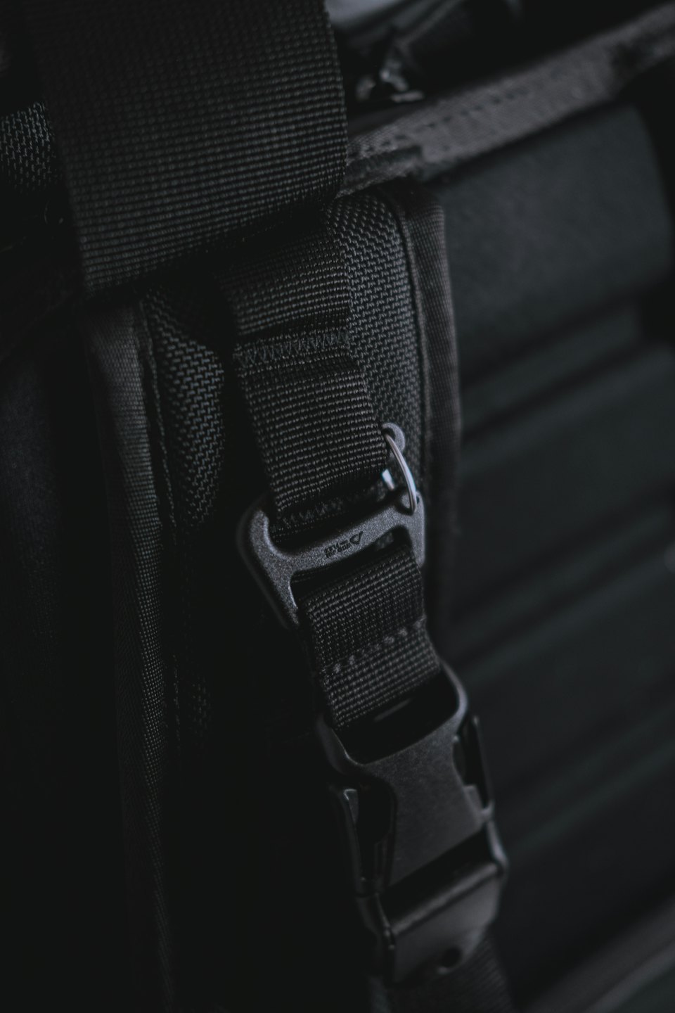 Black woven bag strap with a plastic buckle and adjuster.