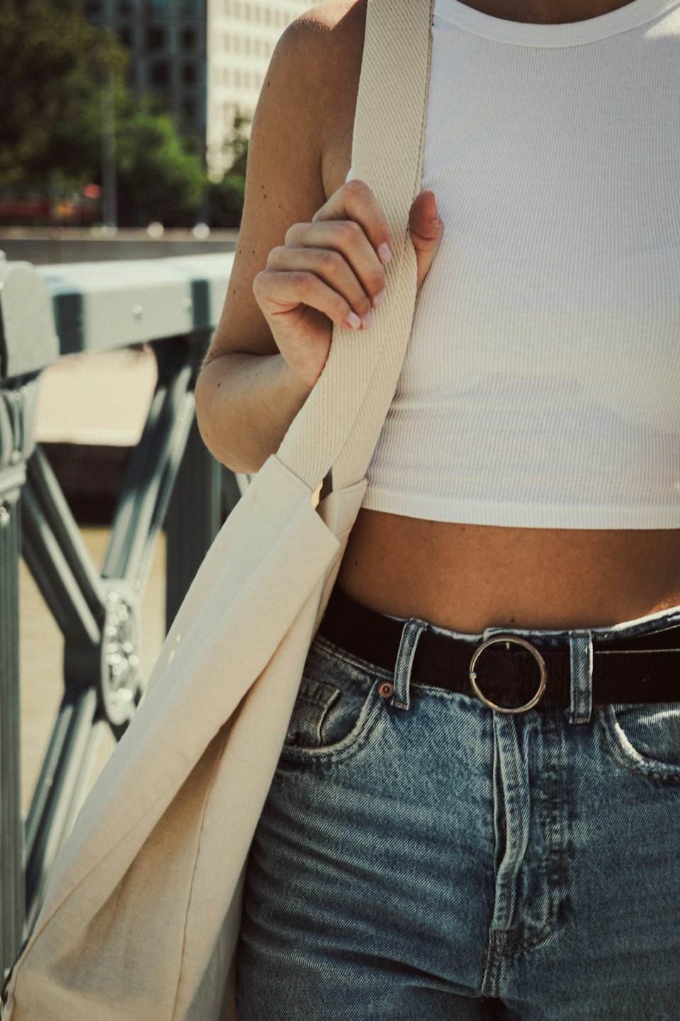 Person in casual clothing carries a cream canvas tote bag.
